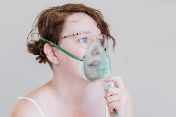 Žena se inhalira s maskom za inhalaciju
