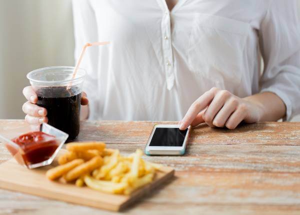 žena sjedi jede fast food i računa kalorije