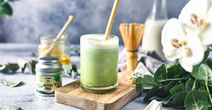 Zeleni matcha prah u smeđoj zdjeli na smeđoj drvenoj površini.