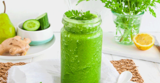 Zeleni smoothie u staklenoj čaši na bijelom stolu.