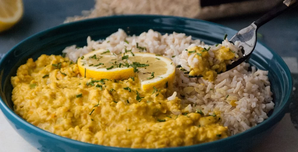 Žuta curry leća s rižom u crnom tanjuru