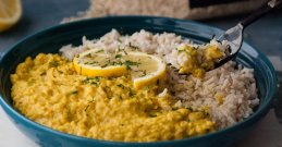 Žuta curry leća s rižom u crnom tanjuru