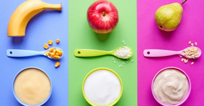 Kašice za bebe u zelenoj i crvenoj boji na bijelom drvenom stolu.