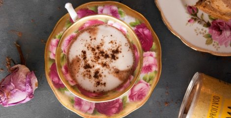 Kremasta lucuma kakao latte u šarenoj šalici za kavu na crnoj pozadini