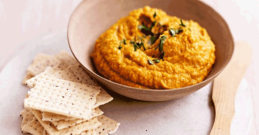 Žuto-narančasti hummus od bundeve u drvenoj zdjeli.